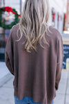 Back view of Model wearing a brown sweater with long sleeves and a round neck.