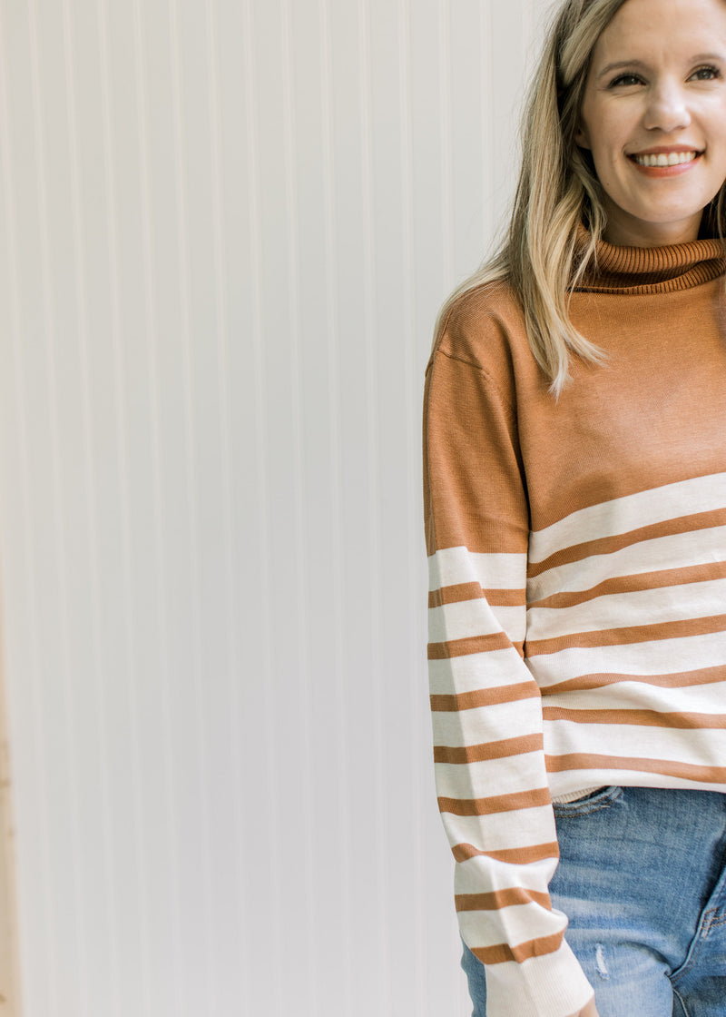 Close up of caramel yolk and turtleneck on a cream and caramel striped sweater. 