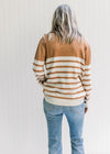 Back view of Model wearing a caramel and cream striped sweater with a turtleneck and long sleeves. 