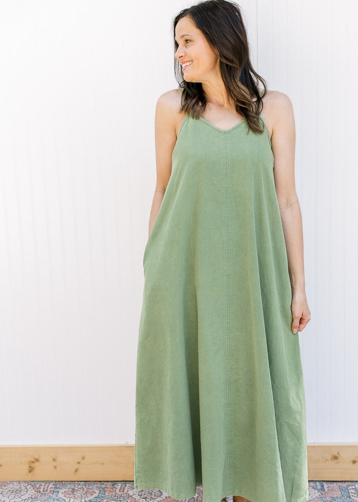 Model wearing a green midi with a v-neck,  adjustable spaghetti straps and pockets.
