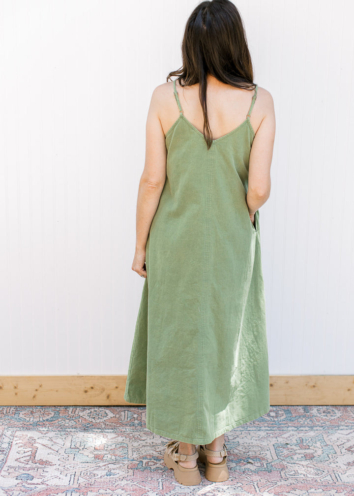 Back view of Model wearing a green midi with a v-neck, adjustable spaghetti straps and pockets.