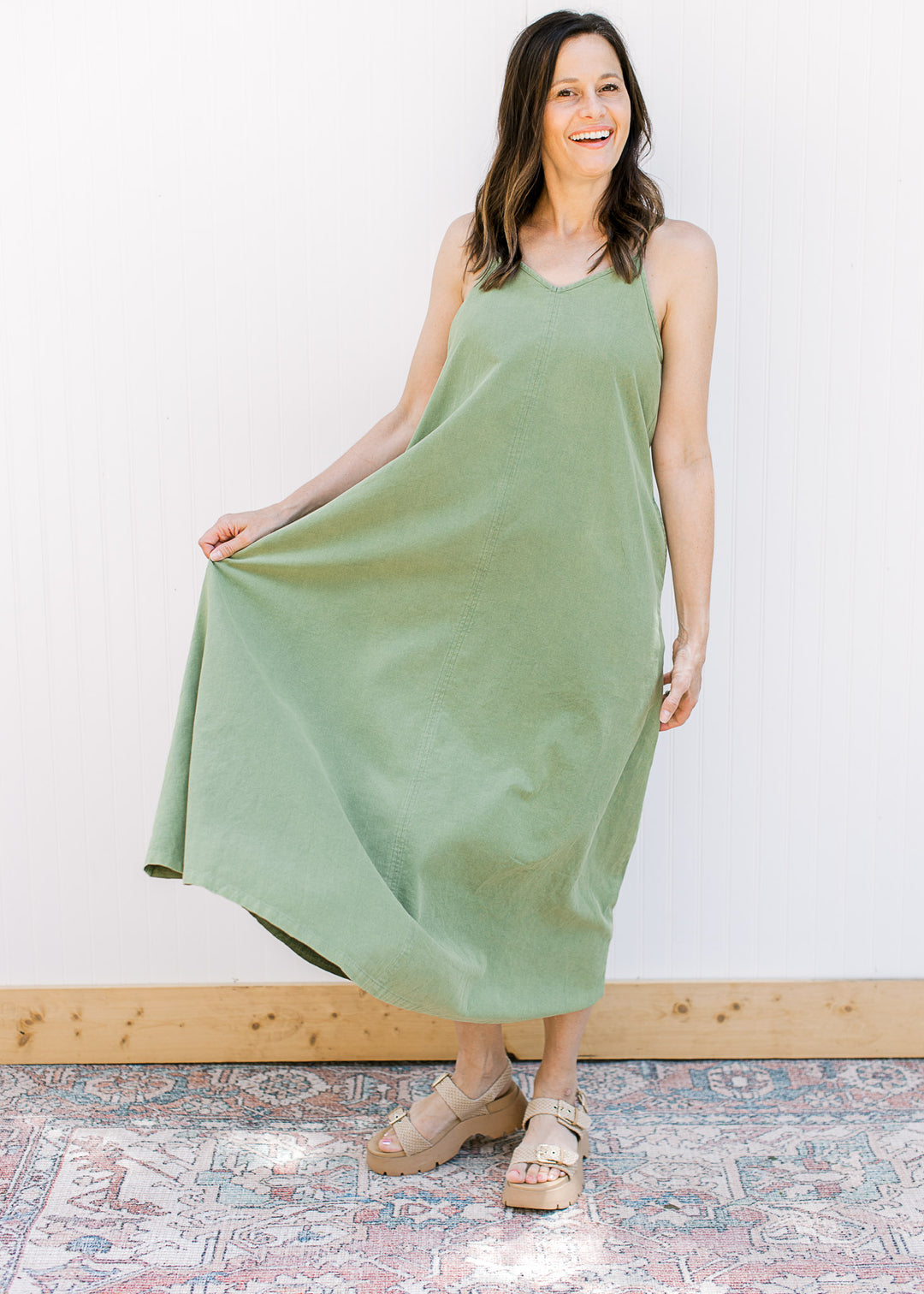 Model wearing wedges and a green midi with a v-neck,  adjustable spaghetti straps and pockets.
