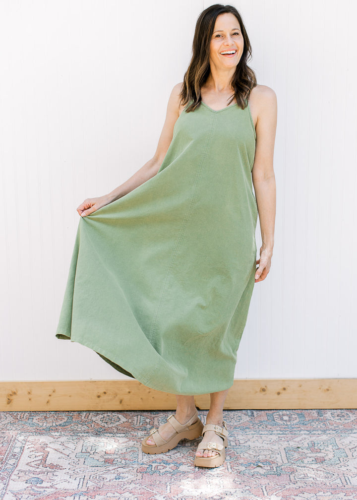 Model wearing wedges and a green midi with a v-neck,  adjustable spaghetti straps and pockets.
