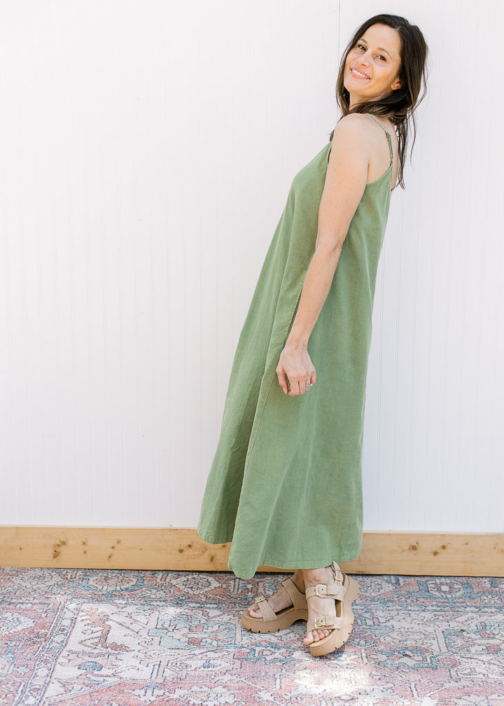 Model wearing a green midi dress with a v-neck,  adjustable spaghetti straps and pockets.
