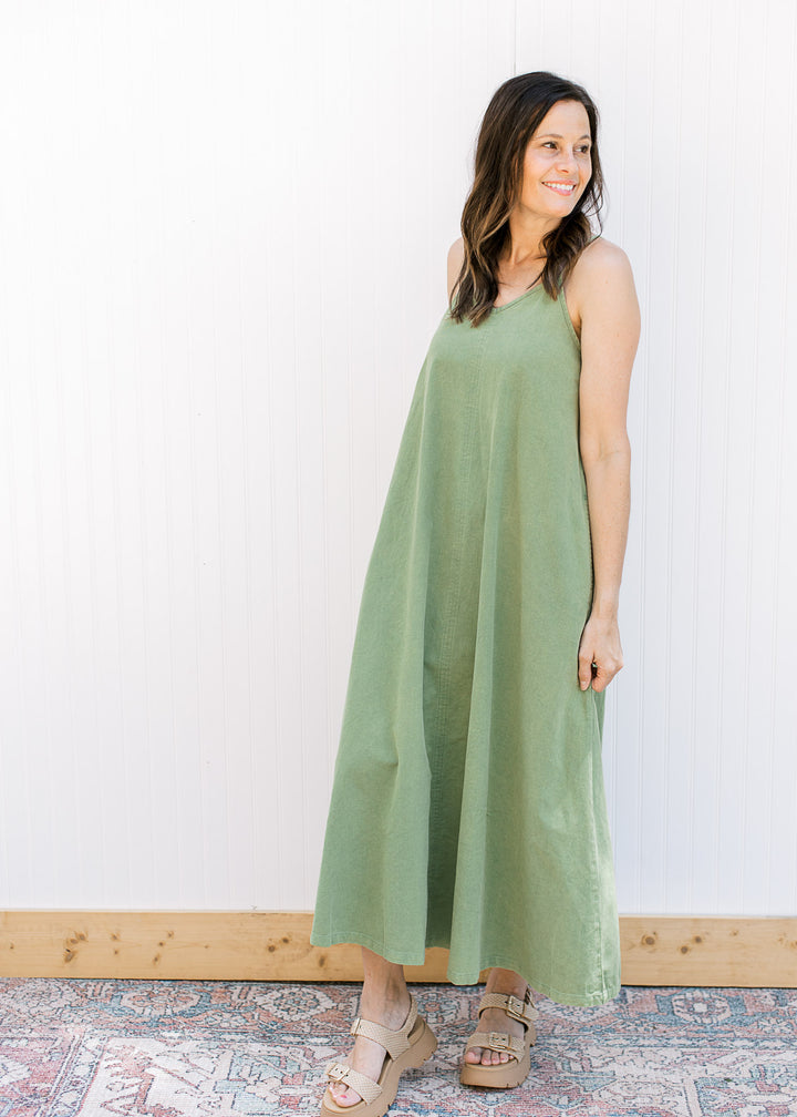 Model wearing a green loose fit midi with a v-neck,  adjustable spaghetti straps and pockets.
