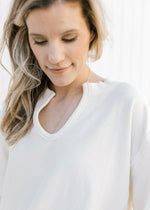 Close up of v-neck on a casual cream top with ribbed detail and long sleeves. 