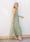 Model wearing wedges and a sleeveless celery green midi with a ribbed knit top and a flowy skirt.