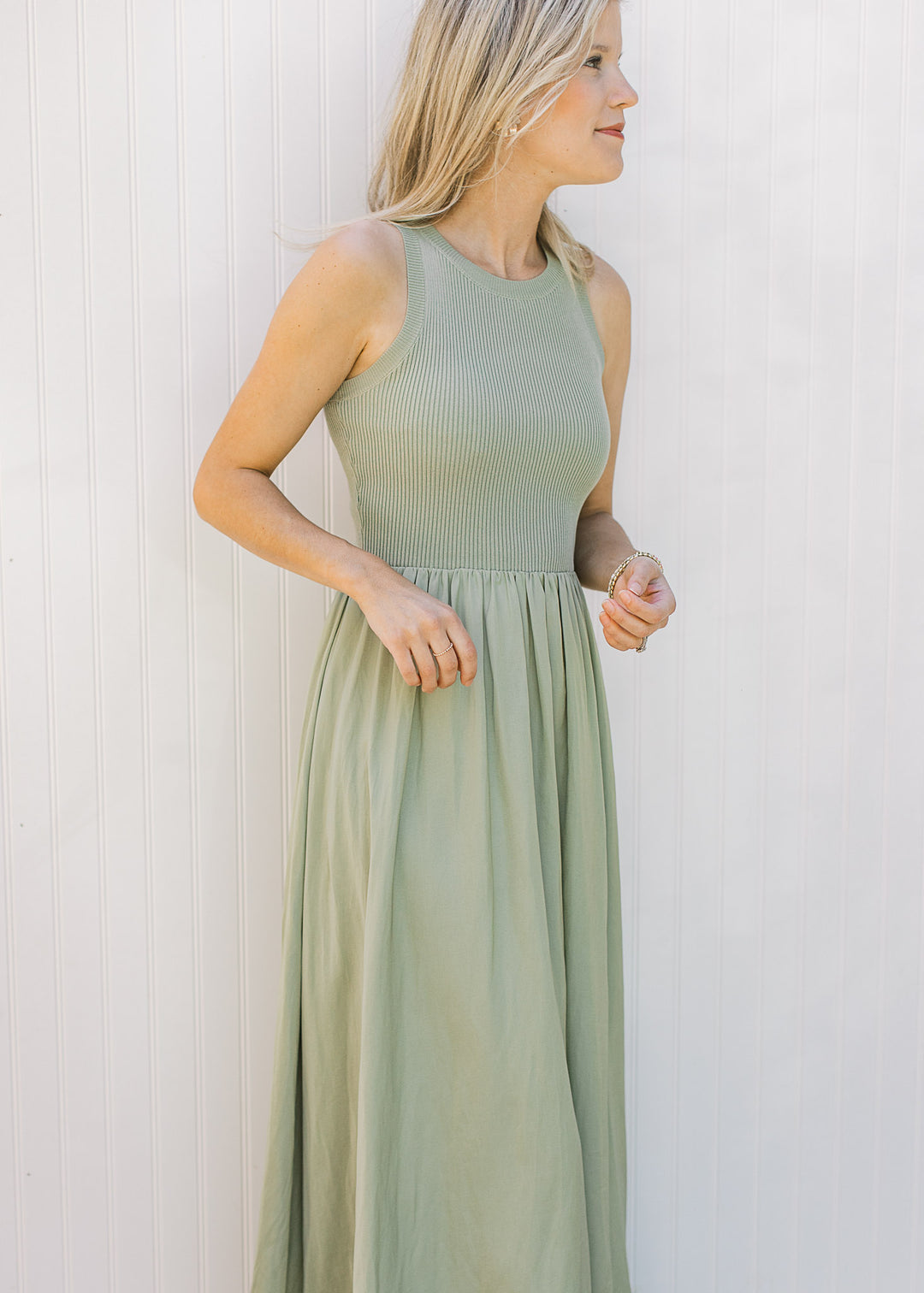 Model wearing a sleeveless celery green midi with a ribbed knit top and a lined flowy skirt.