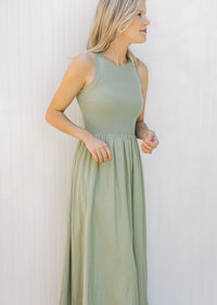 Model wearing a sleeveless celery green midi with a ribbed knit top and a lined flowy skirt.