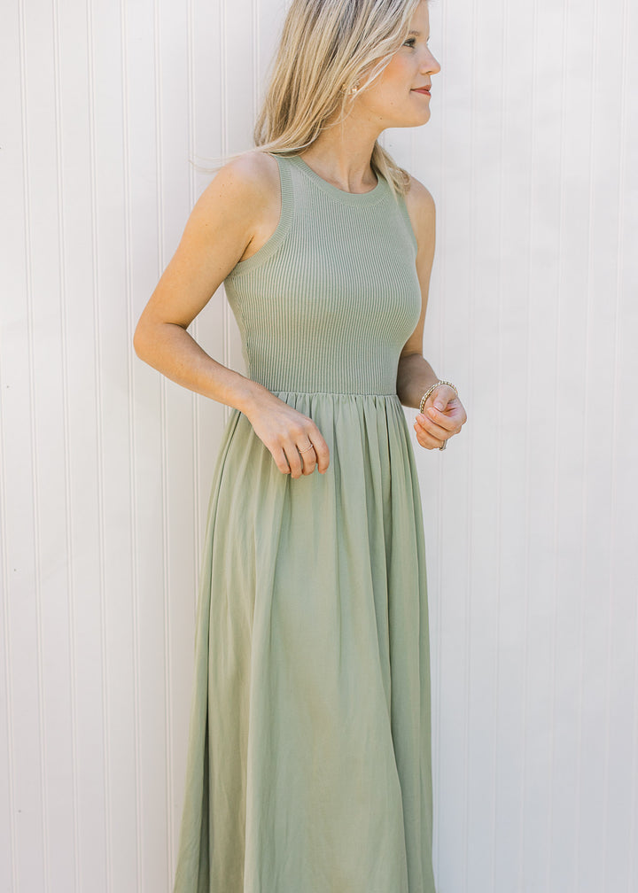 Model wearing a sleeveless celery green midi with a ribbed knit top and a lined flowy skirt.