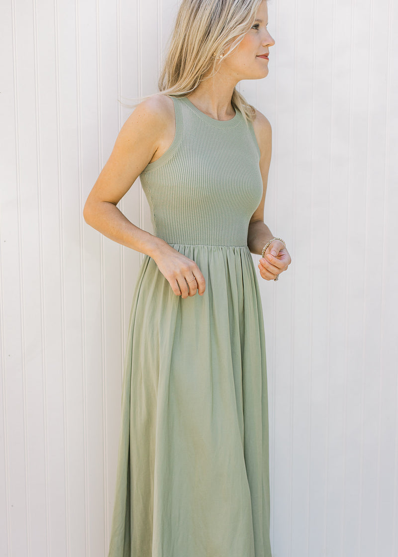 Model wearing a sleeveless celery green midi with a ribbed knit top and a lined flowy skirt.
