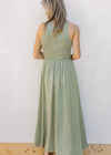 Back view of Model wearing a sleeveless celery green midi with a ribbed knit top and a flowy skirt.