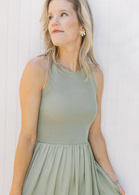 Close up of sleeveless knit ribbed top on a celery green midi with a lined flowy skirt. 