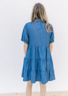 Back view of Model wearing a blue button up above the knee dress with bubble short sleeves.