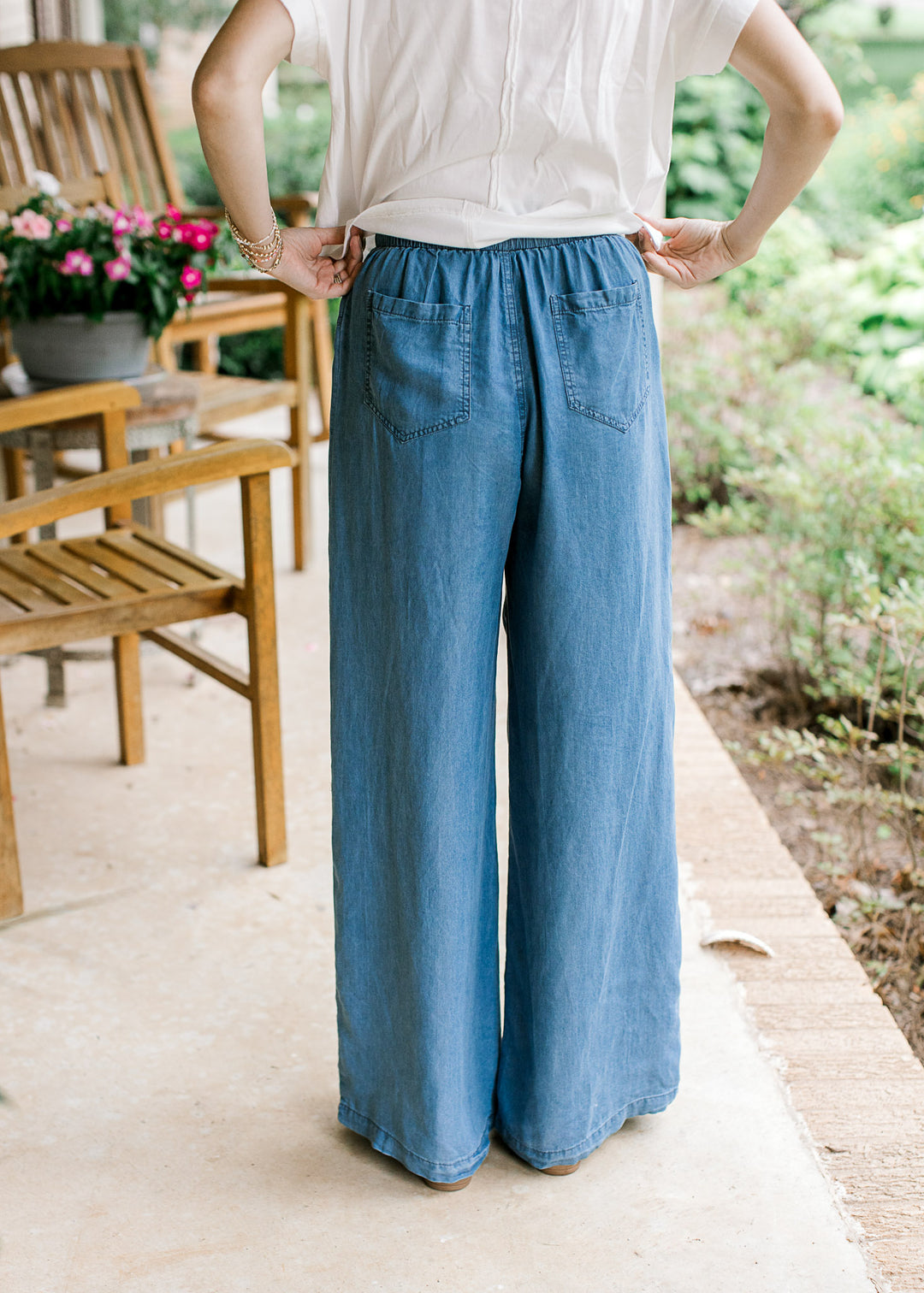 Back view of Model wearing chambray wide leg pants with an elastic waist and back pockets.