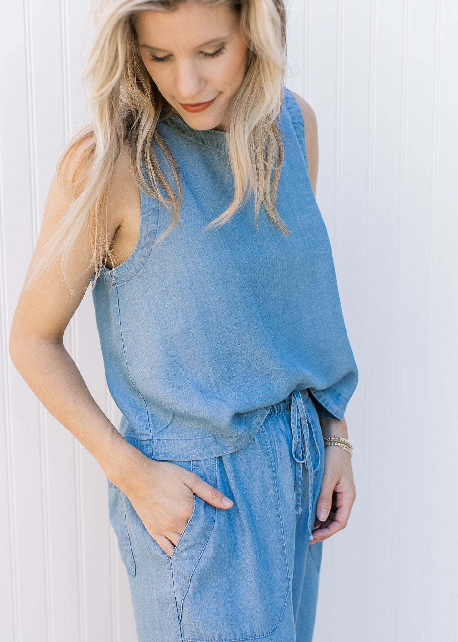 Side view of model wearing a chambray set with a cropped sleeveless top and wide leg bottoms.
