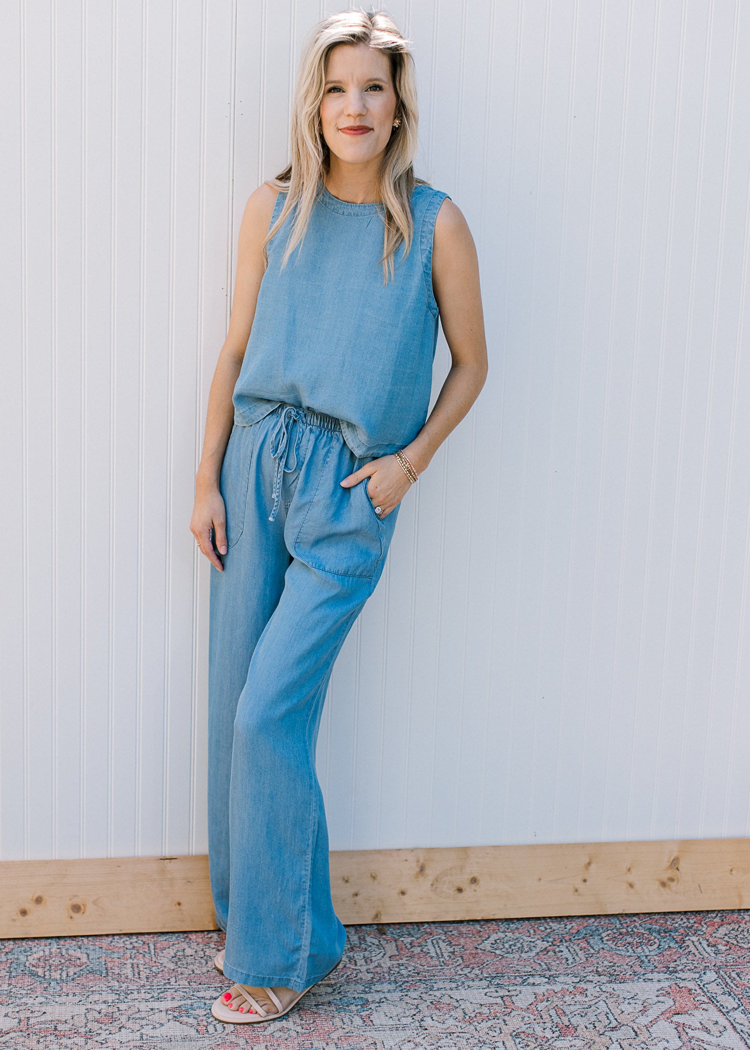 Model wearing sandals and a chambray set with a sleeveless top and wide leg bottoms.