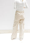 Back view of Model wearing champagne wide leg, cargo bottoms with elastic and a tie at the waist. 