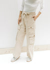 Model wearing sneakers with champagne wide leg, cargo bottoms with elastic and a tie at the waist. 