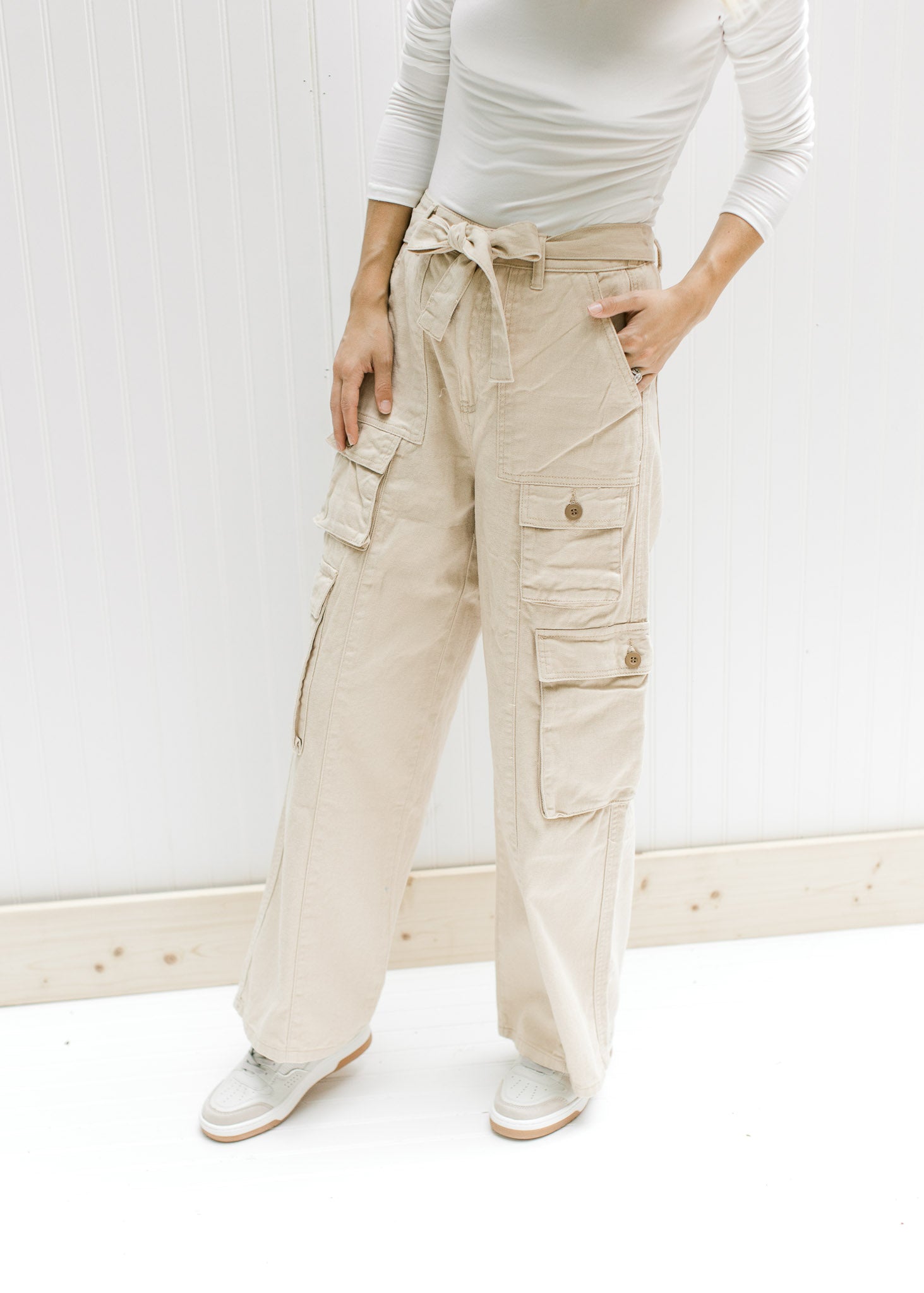Model wearing sneakers with champagne wide leg, cargo bottoms with elastic and a tie at the waist. 