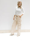 Model wearing a white top with champagne wide leg cargo pants with elastic and a tie at the waist.
