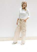 Model wearing a white top with champagne wide leg cargo pants with elastic and a tie at the waist.