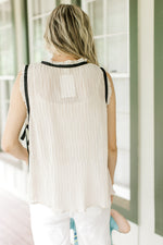 Back view of a champagne sleeveless top with a plisse material and black accents. 