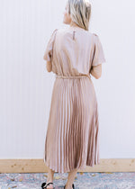 Back view of Model wearing a champagne midi with a pleated skirt and short sleeves. 