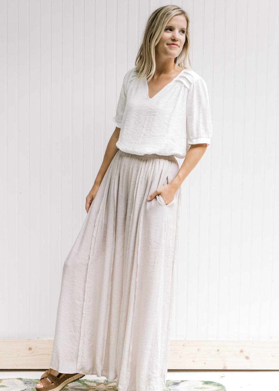 Model wearing champagne wide leg pants with an elastic waist, pocket and a polyester material.