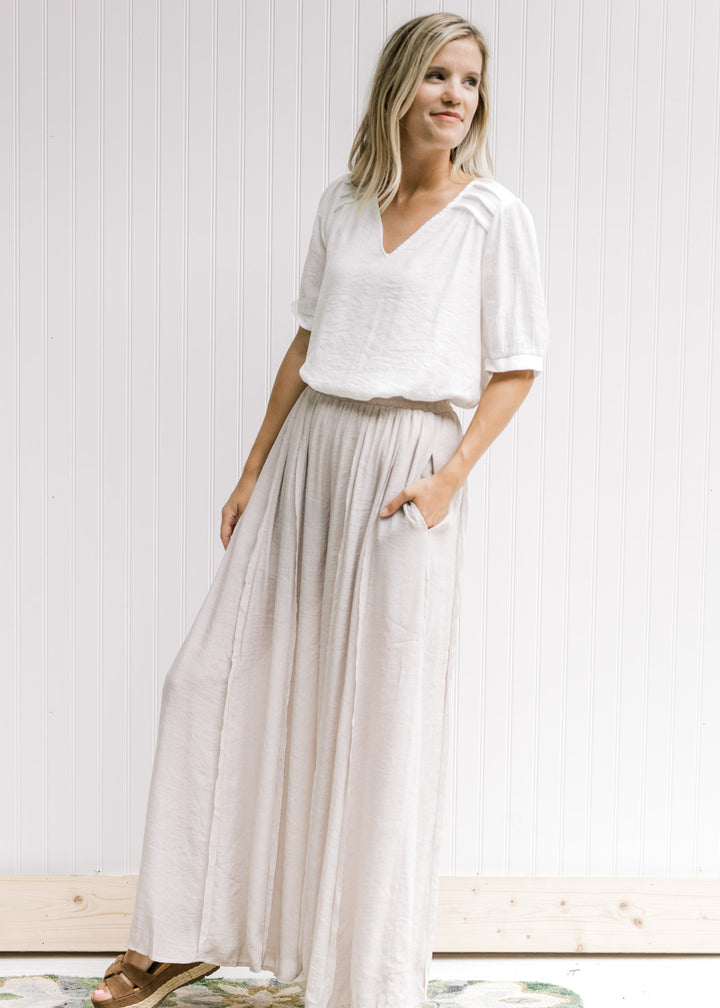 Model wearing champagne wide leg pants with an elastic waist, pocket and a polyester material.