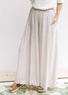 Model wearing sandals with champagne wide leg pants with an elastic waist and a polyester material.