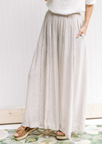 Model wearing sandals with champagne wide leg pants with an elastic waist and a polyester material.