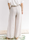 Back view of Model wearing champagne wide leg pants with an elastic waist and pockets. 