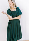 Model wearing a deep green bubble dress with a square neck and bubble short sleeves. 