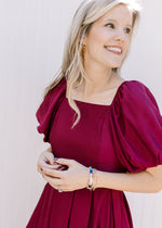 Close up of square neck and bubble short sleeves on a deep cranberry above the knee dress. 