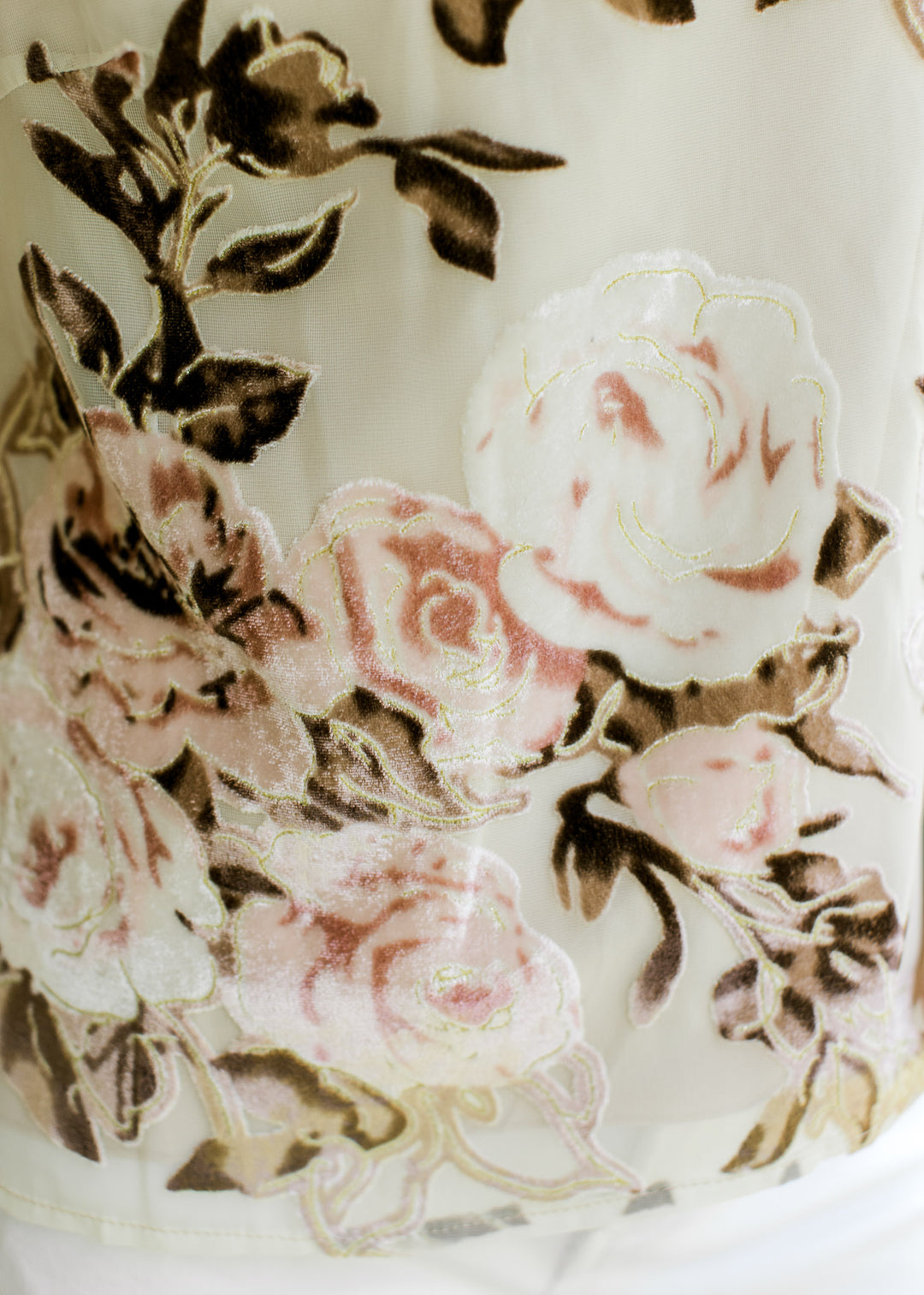 Close up of pink and brown velvet floral on a cream sleeveless top with a mock neckline. 