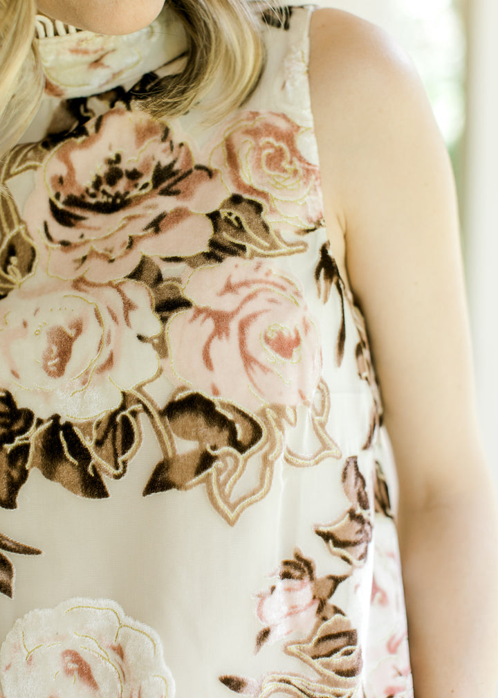 Close up of mock neck with cream lace on a sleeveless cream top with pink and brown floral.