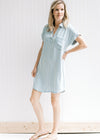 Model wearing a light blue and cream striped v-neck above the knee dress with cuffed short sleeves. 