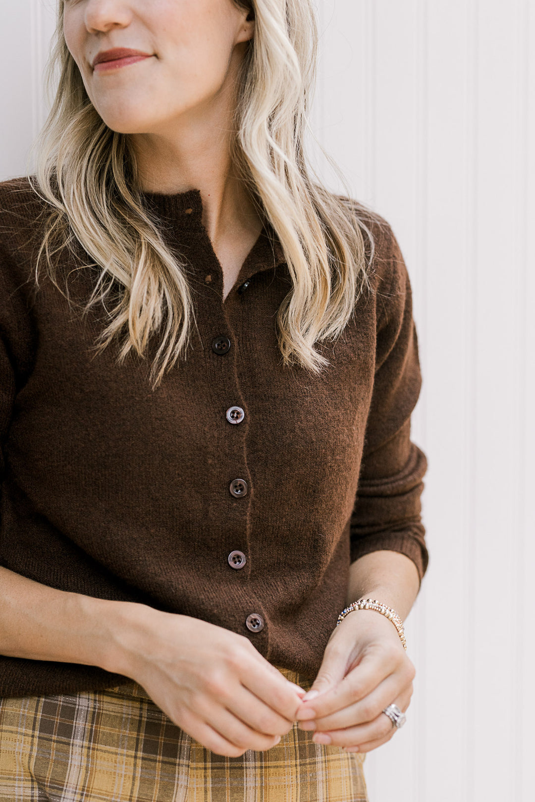 Model wearing an ultra soft brown knit button up sweater with long sleeves and a round neck.