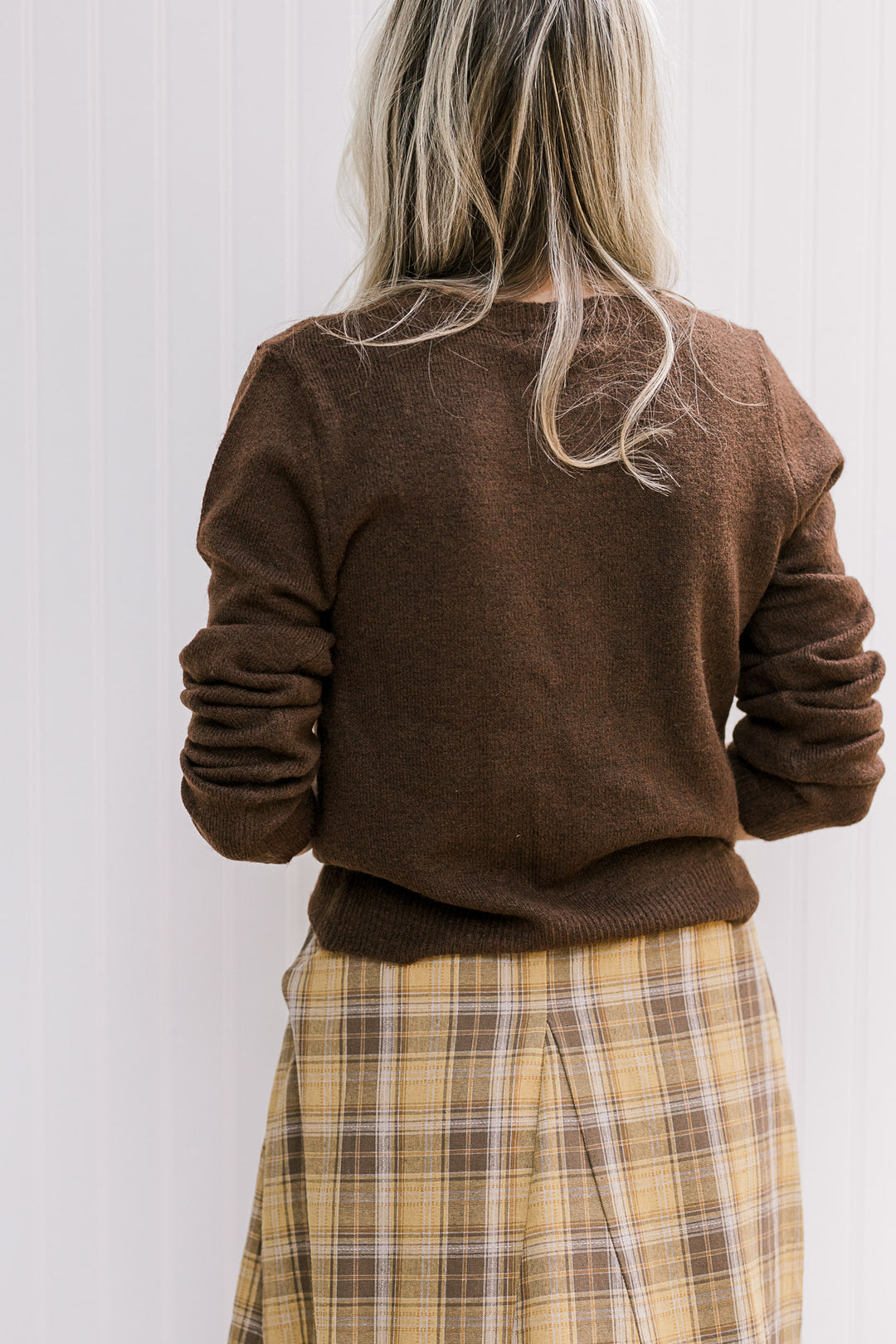 Back view of Model wearing an ultra soft brown cardigan with long sleeves and a round neck.