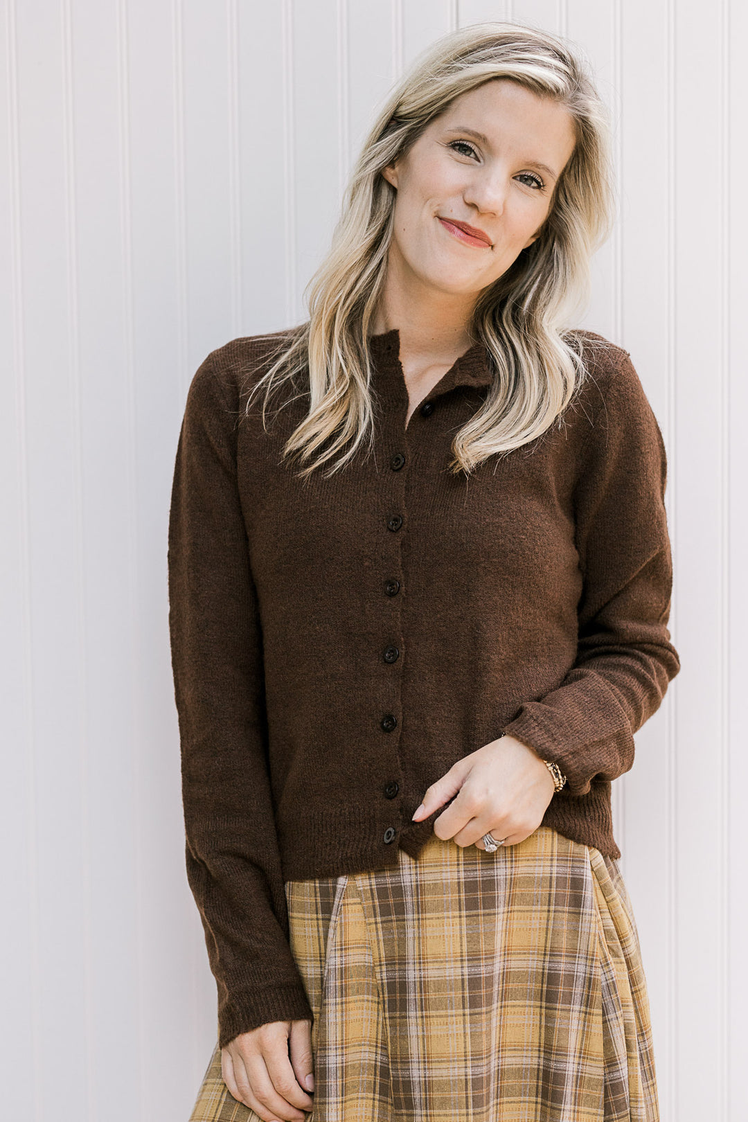 Model wearing a mustard and brown midi with a brown cardigan with long sleeves and a round neck.