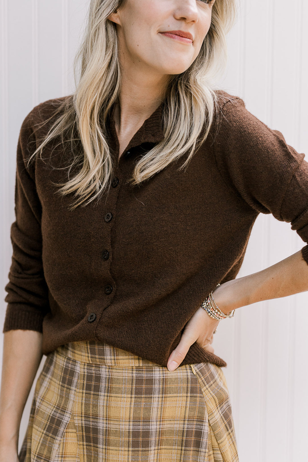 Model wearing a brown knit button up cardigan with long sleeves and a round neck.