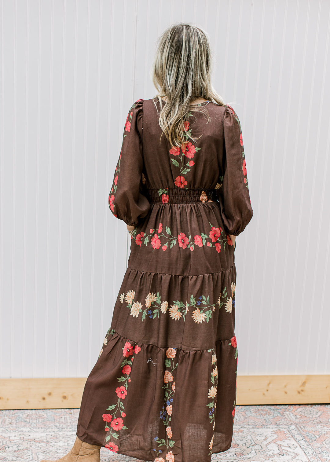 Back view of Model wearing a chocolate maxi with floral, elastic waist, pockets and 3/4 sleeves. 