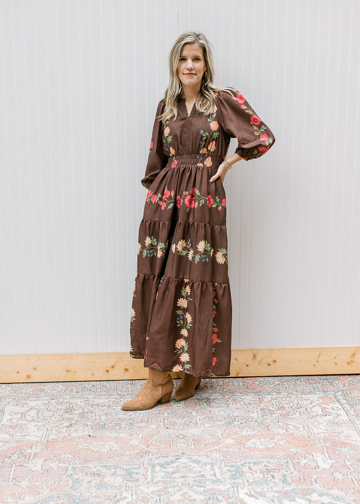 Model wearing boots and a chocolate maxi with floral, elastic waist and 3/4 sleeves. 
