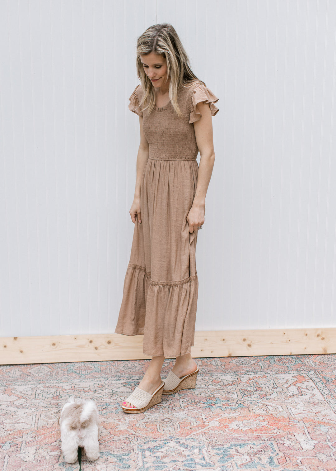 Model wearing heels with a light brown midi with a smocked bodice and ruffle cap sleeves.