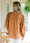 Back view of Model wearing a cinnamon blouse with long sleeves and v-neck.