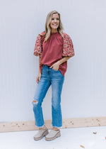 Model wearing jeans and mules with a cinnamon top with embroidery on bubble short sleeve.