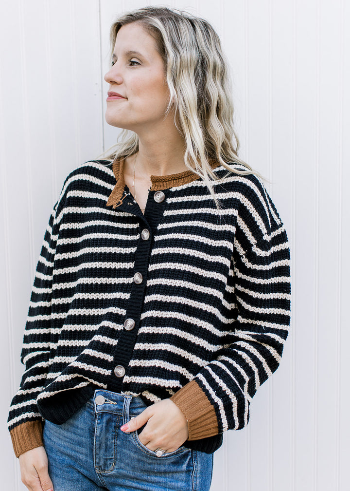 Model wearing a black and white striped long sleeve cardigan with a button front. 