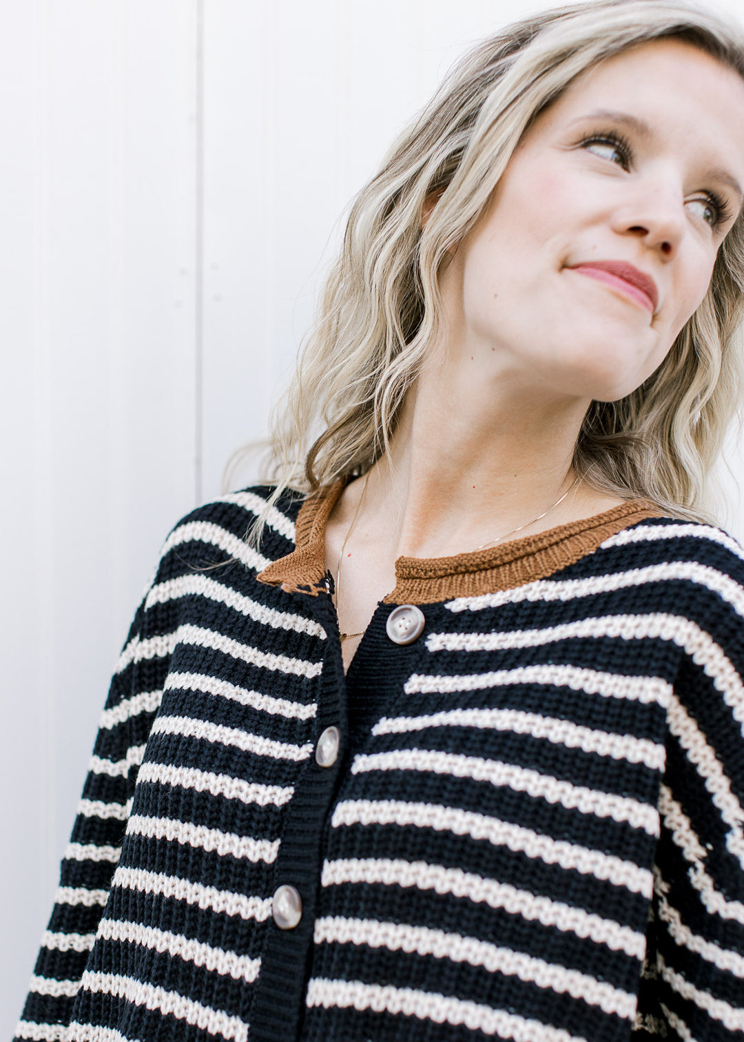 Close up of buttons and brown collar on a black and cream button up, long sleeve cardigan. 