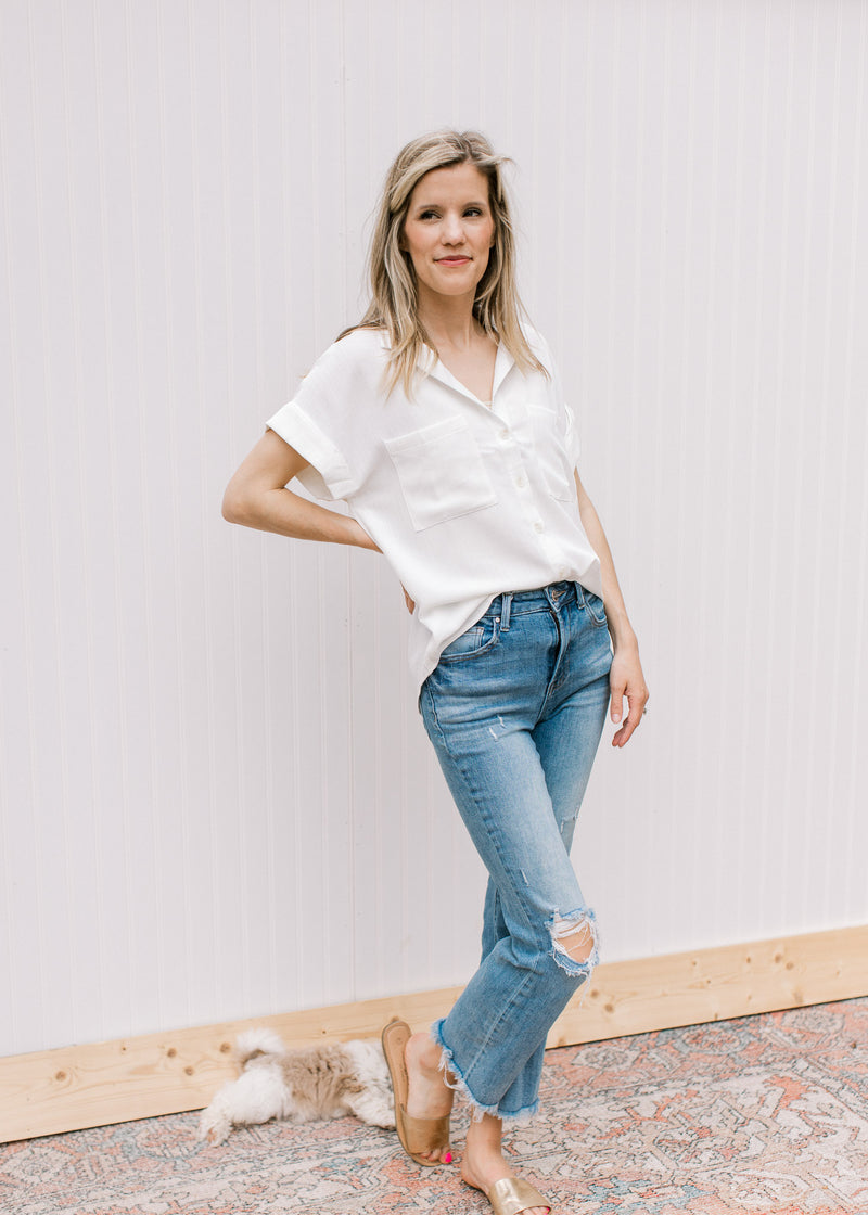 Model wearing jeans with a white button down with patch pockets and cuffed short sleeves.